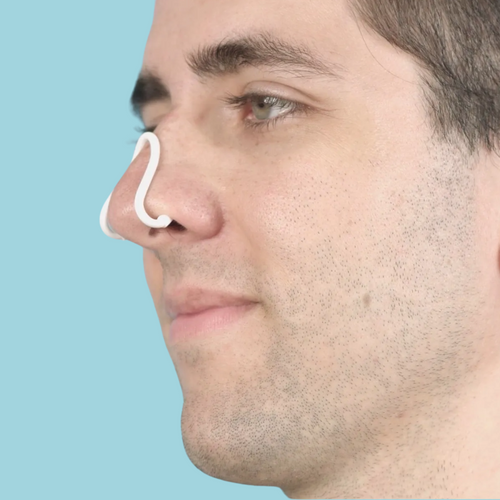 Person inserting Nasalaid™ nasal dilator into their nostrils for improved airflow and breathing.”